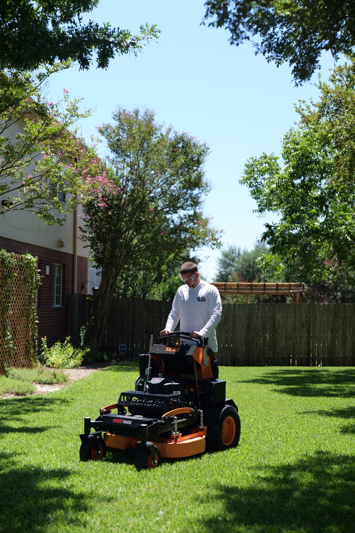 Go Yard Landscaping crew mowing a backyard lawn with a stand-on mower